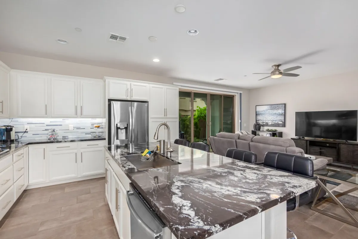 A bright kitchen with a prominent island, modern appliances, and an adjacent living area. The layout invites hosting dinner parties or enjoying a casual coffee in the morning light.