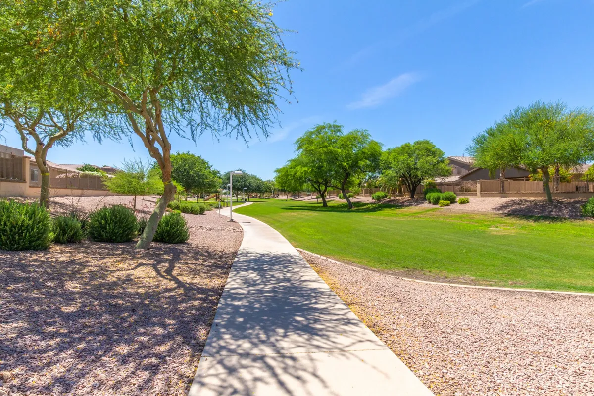 This serene image captures a meandering pathway edged by lush green grass, decorative trees, and landscaped bushes. The peaceful setting encourages strolls and gatherings, promoting relaxation and connection with nature.
