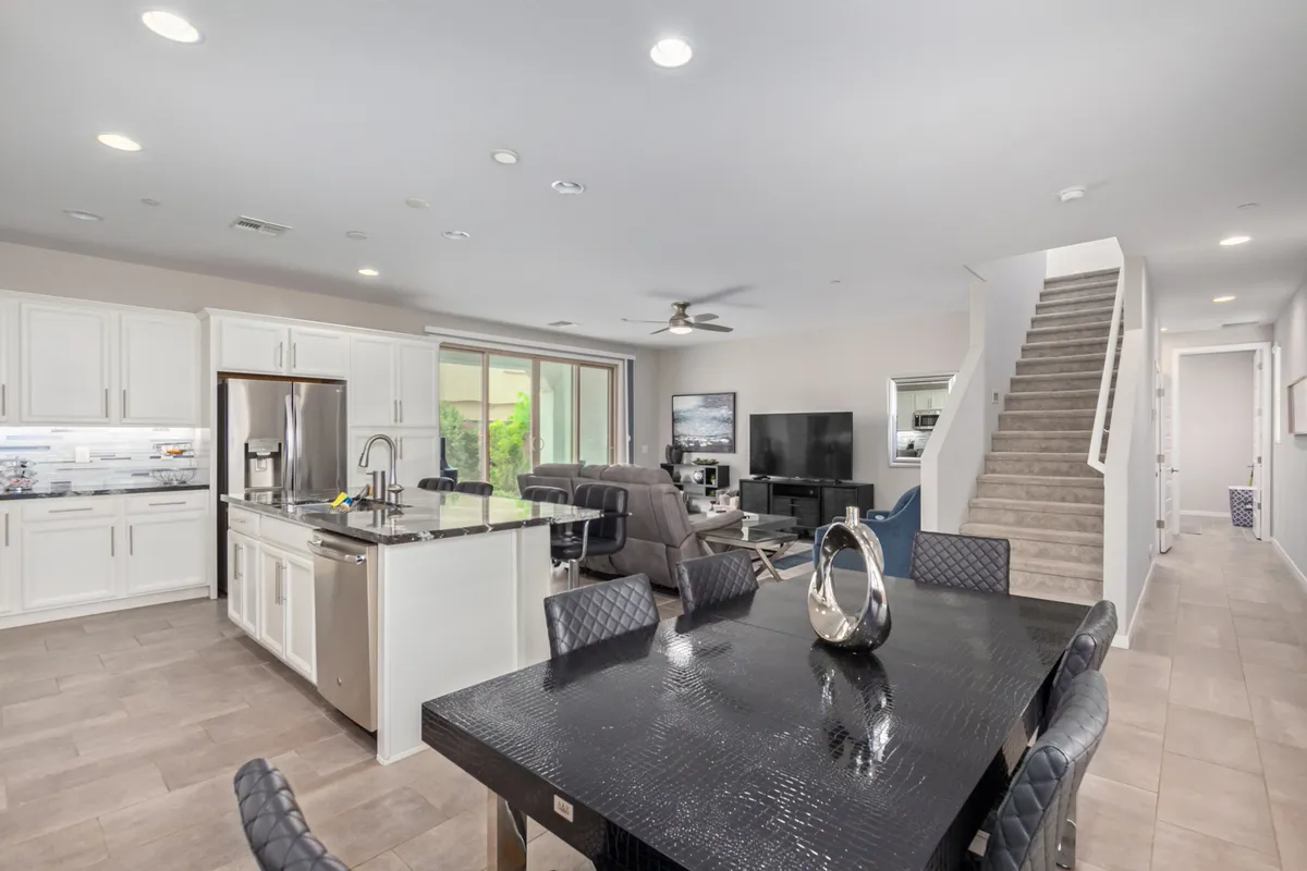 A spacious, modern open-plan area featuring a kitchen island, dining table, and comfortable living area seating. The large windows fill the space with natural light, and the layout encourages easy flow between cooking, dining, and relaxing. The overall atmosphere is contemporary and welcoming, inviting groups and families to gather.