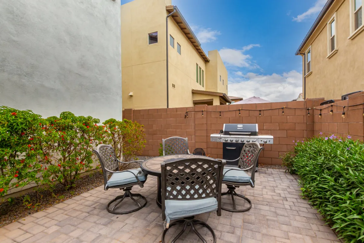 This image shows an inviting backyard scene with a dining table, grill, and well-trimmed hedges, suggesting a space perfect for outdoor meals, barbecues, and gathering with family and friends. The relaxed atmosphere and ample space encourage group activities and togetherness.